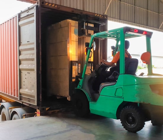 Man driving a forklift to remove goods from a container