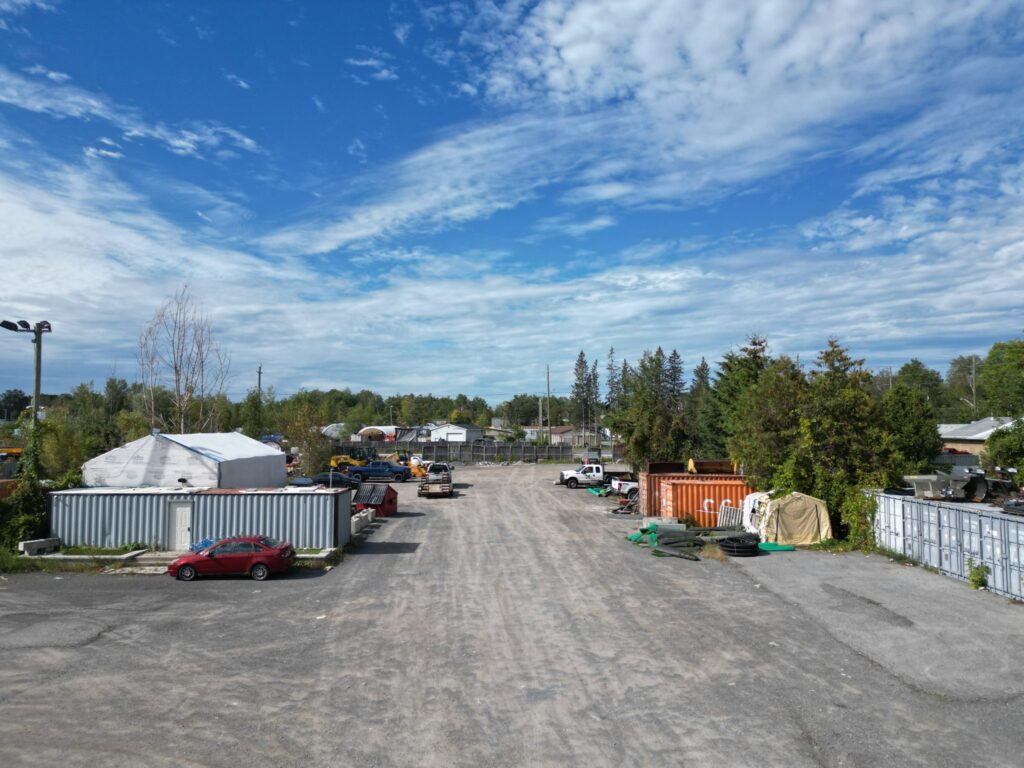 Ground-level view down the open gravel yard at 2538 Leitrim Road